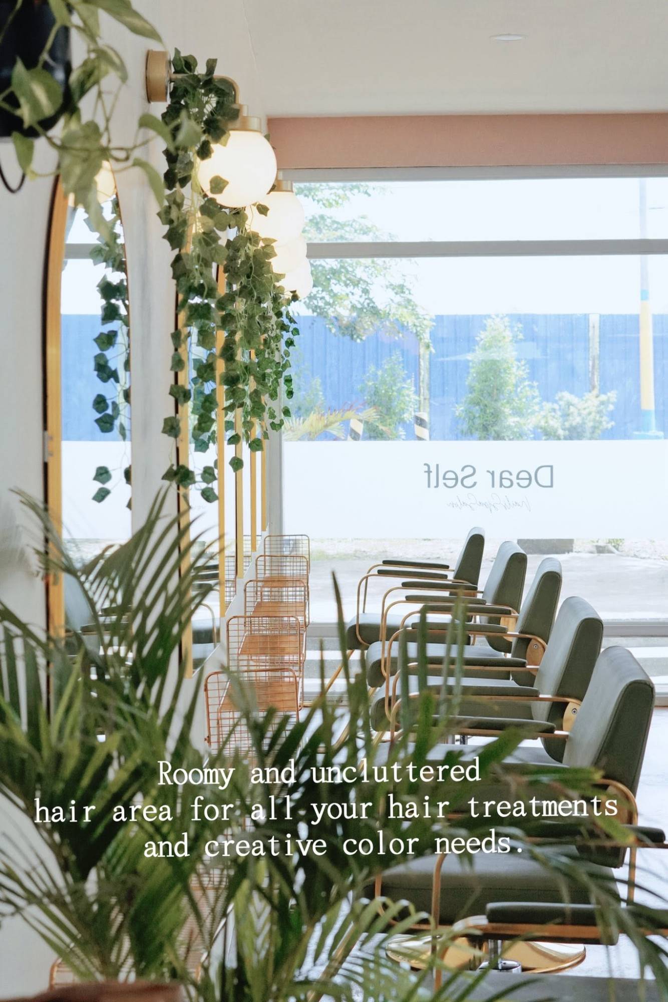 Salon area with green styling chairs, arched mirrors and hanging plants